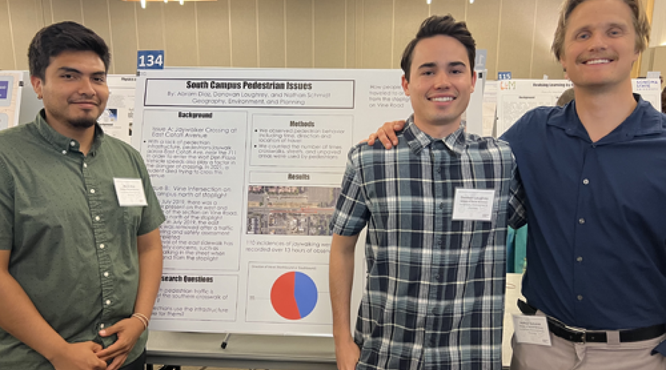 Three students in front of poster in reserach colloquium